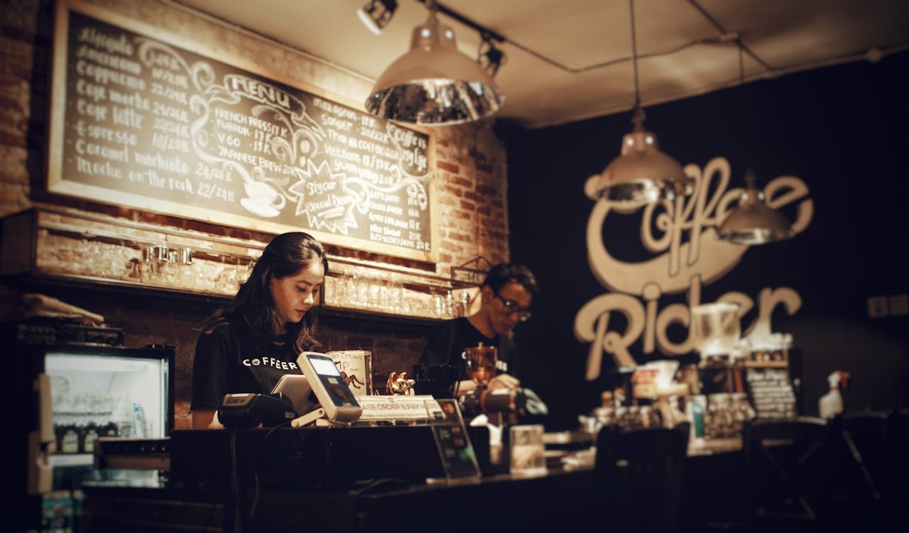 Baristas preparing coffee at Coffee Rider, Karawaci. Cozy indoor setting with menu board.